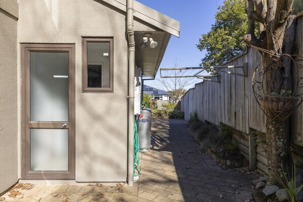 A narrow pathway leading to a building with a door and a window.