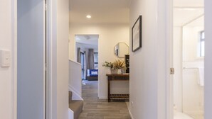 A hallway with a wooden floor, a staircase, a wall-mounted lamp, and a welcome sign. - The Tui`s Nest - central to town (Taupō)