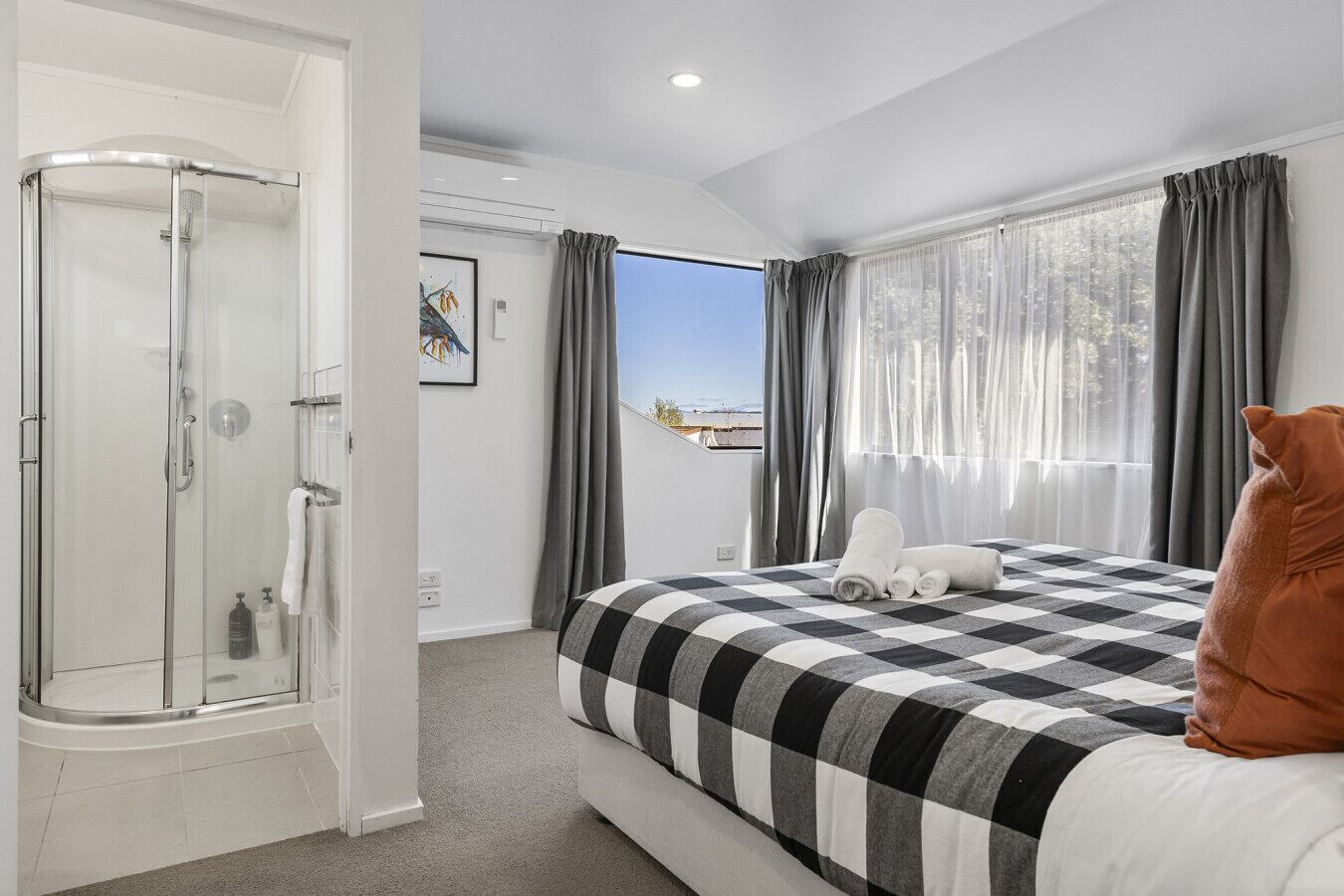 A hotel room with a bed, a shower, and a view of the outdoors.