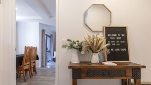 A reception area with a wooden table displaying a welcome sign, a vase with dried plants, and a mirror on the wall. - The Tui`s Nest - central to town (Taupō)