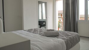 A bedroom with a bed, a door, and a view of the outside.