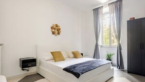 A modern bedroom with a large bed, a bedside table, a small plant, and a wardrobe. - Vatican Area | Stylish 2BR + Fast Wi-Fi & A/C (Roma)