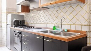 A kitchen with a stainless steel sink, a stove, and a coffee maker. - Vatican Area | Stylish 2BR + Fast Wi-Fi & A/C (Roma)