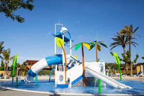 Um parque aquático com um grande tobogã, palmeiras e um céu azul transparente.