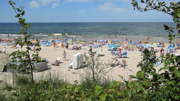 A beach with umbrellas and sun loungers, a sandy shore, and the ocean in the background. - Mobile Home in Kolczewo With a Terrace (gmina Wolin)