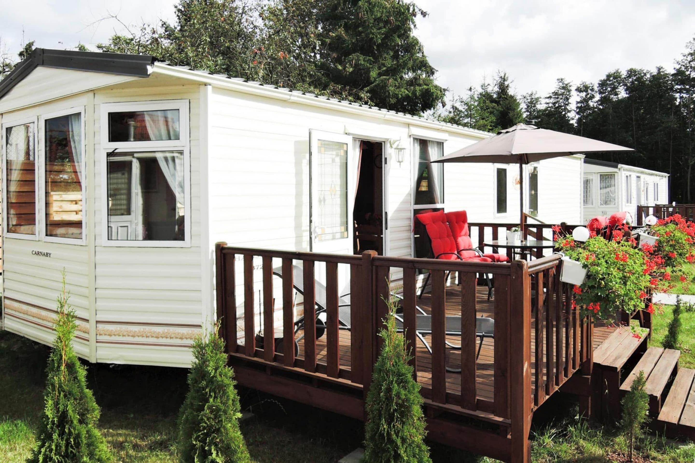 A mobile home with a deck, a dining area, and a small garden.