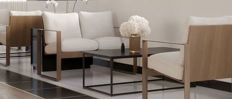 Una sala moderna con un sofá, dos sillones, una mesa de centro y flores decorativas.