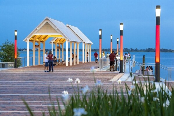 A pier with a covered seating area and people walking along it.