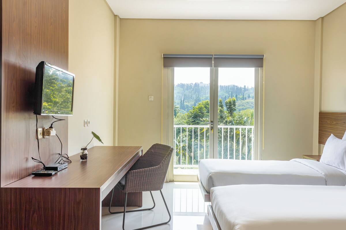 Quarto de hotel com escrivaninha, cadeira e duas camas.