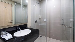 A modern bathroom with a black countertop, white sink, and a glass shower enclosure. - Pelangi Hotel at Artotel Pelangi Park (Bogor)