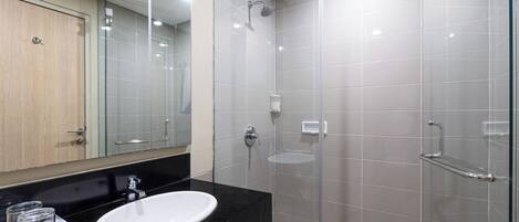 Un baño moderno con encimera negra, lavabo blanco y cabina de ducha de vidrio.