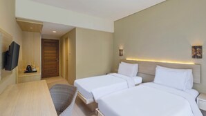 A hotel room with two beds, a TV, a desk, and a chair. - Pelangi Hotel at Artotel Pelangi Park (Bogor)