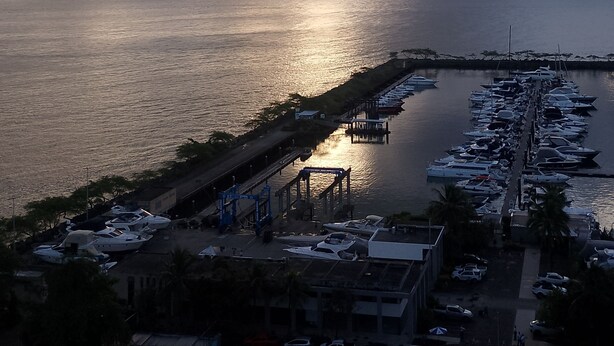 Un puerto deportivo con barcos amarrados, un muelle y vista al mar bajo un cielo nublado.