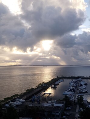 A marina with boats docked, a pier, and a view of the sea under a cloudy sky. - Salvador Hotel (Nazaré Salvador)
