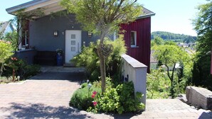 A two-story house with a front porch, a mailbox, and a small garden with flowers.