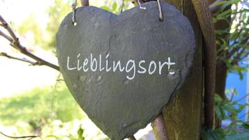 Une pierre en forme de cœur sur laquelle est inscrit le mot « Lieblingsort », suspendue à une branche d’arbre.