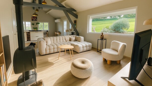 A spacious living room with a large sectional sofa, a round ottoman, a television, and a fireplace. - The Norman chalet (Les Champeaux)
