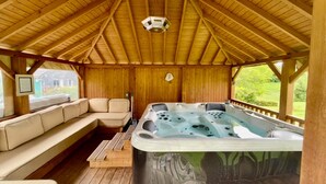 A wooden deck with a hot tub, a sofa, and a framed picture on the wall. - The Norman chalet (Les Champeaux)