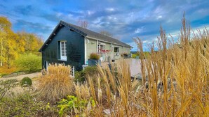 A two-story house with a dark exterior, a front porch, and a driveway. - The Norman chalet (Les Champeaux)