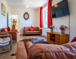 A living room with a sofa, a wooden cabinet, a TV, and a clock on the wall.