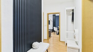A modern room with a wooden floor, a bench with a towel, a wooden door, and a white wall.