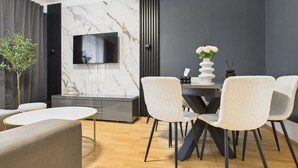 A modern dining area with a marble wall, a flat-screen TV, and a dining table with chairs.
