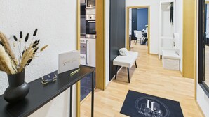A modern hotel lobby with a reception desk, a guest book, a doormat, and a view into the dining area.