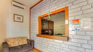 Ein Empfangsbereich mit Backsteinwand, einem Holztresen, einer Couch und einem gerahmten Bild an der Wand.
