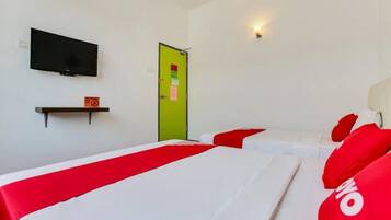 A hotel room with two beds, a television on the wall, a green door, and a shelf with a sign.