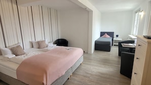 Ein modernes Hotelzimmer mit einem großen Bett, einem Schreibtisch, einem Stuhl und einem Fernseher.