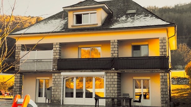Ein zweistöckiges Haus mit Balkon, Garage und einer Terrassenfläche.