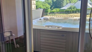 Ein Whirlpool mit Bedienfeld, Glastür und Blick auf Grünflächen sowie ein Gebäude im Freien.