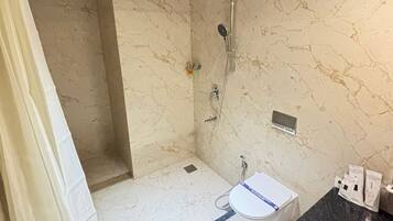A bathroom with a shower, a sink, and a marble wall.