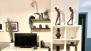 Ein modernes Wohnzimmer mit Flachbildfernseher, weißen Möbeln, Dekoration und Holzboden.