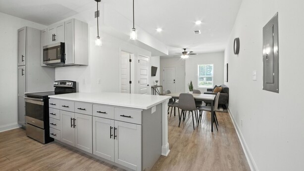 A modern kitchen with white cabinetry, a central island, and a dining area with a table and chairs.