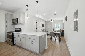 A modern kitchen with white cabinetry, a central island, and a dining area with a table and chairs.