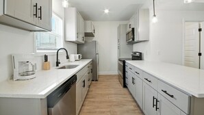 A modern kitchen with white cabinetry, stainless steel appliances, and a central island.