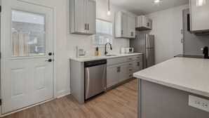 A modern kitchen with white cabinetry, stainless steel appliances, and a dishwasher.