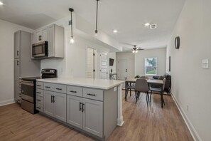 Una cocina moderna con gabinetes grises, electrodomésticos de acero inoxidable e iluminación colgante.