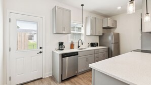 A modern kitchen with stainless steel appliances, white cabinetry, and pendant lighting.