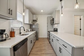 A modern kitchen with white cabinetry, stainless steel appliances, and pendant lighting.