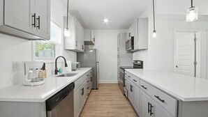A modern kitchen with white cabinetry, stainless steel appliances, and pendant lighting. - Arte Luxury townhomes O5 I Comfy 2 Bed 2.5 Bath (Clarksville)