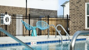 A swimming pool with a lifebuoy, two blue chairs, and a metal ladder. - Arte Luxury townhomes O5 I Comfy 2 Bed 2.5 Bath (Clarksville)