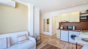 A compact living space with a sofa, kitchenette, washing machine, and a small dining area. - N&J - CASA SOLANA - Terrace - Centre (Niza)