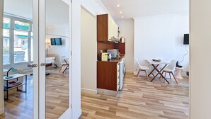 A modern kitchen with wooden cabinets, a built-in oven, and a dining area with white chairs and a small table. - N&J - CASA SOLANA - Terrace - Centre (Niza)