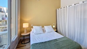 A hotel room with a bed, a bedside table with a lamp, a window with an air conditioning unit, and a view of the outside balcony. - N&J - CASA SOLANA - Terrace - Centre (Niza)