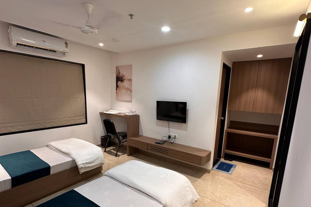 A hotel room with a bed, a desk, a TV, and a wardrobe.
