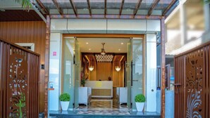 A hotel entrance with a green carpet, a reception desk, and decorative wooden panels. - Hotel S K Executive (Rajgurunagar)