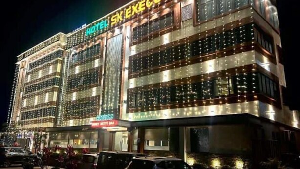 A multi-story hotel with illuminated signage, a parking area, and a visible entrance. - Hotel S K Executive (Rajgurunagar)