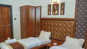 A hotel room with two single beds, a wooden wardrobe, and a tufted headboard. - Hotel S K Executive (Rajgurunagar)